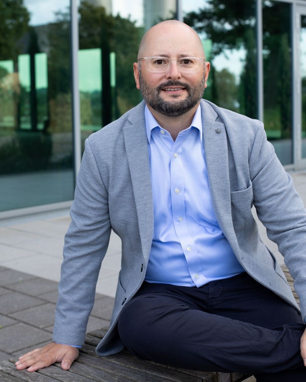 Dr. Jens Träger, Gründer von Truinorva, im grauen Sakko sitzend vor moderner Glasfassade; halbnahes Porträt.